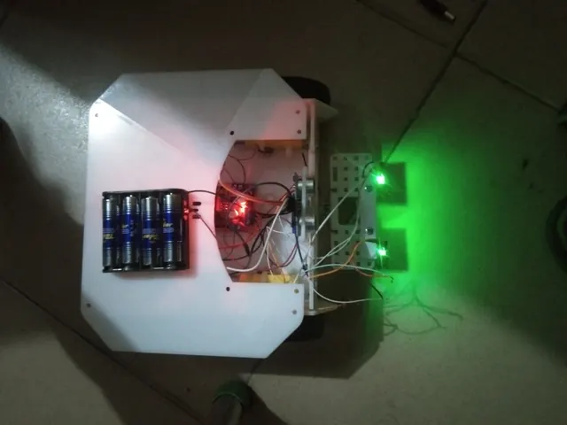 Three-wheeled robot chassis lit by green indicator LEDs